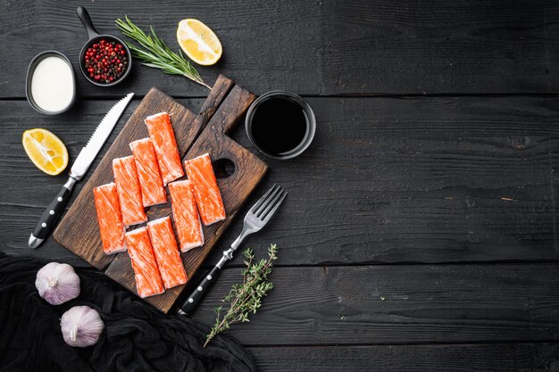 Fresh Crab meat stick surimi  set, on wooden cutting board, on black wooden table background, top view flat lay , with copyspace  and space for text