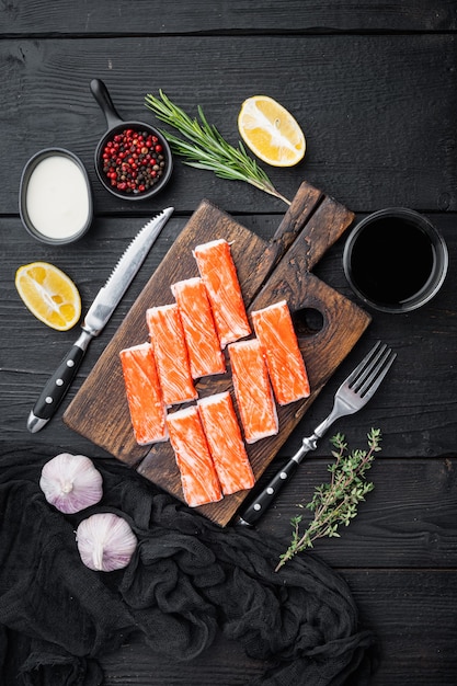 Polpa di granchio fresca stick surimi con nuoto blu set di granchio, sul tagliere di legno, sul tavolo in legno nero tavolo, vista dall'alto laici piatta