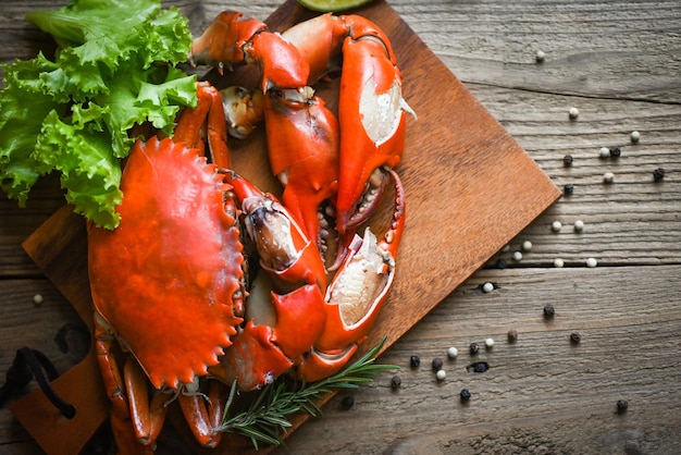 Fresh crab on wooden plate boiled or steamed crab red in the\
restaurant claw crab cooking food seafood plate with chili herbs\
spices salad