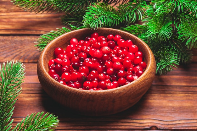 Fresh cranberries in a wooden bowl and fir branches