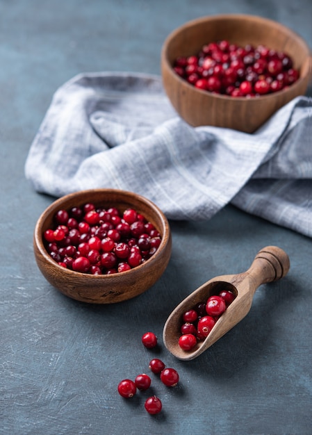 Fresh cranberries in a wooden bowl with napkin on a dark blue wooden background. Macro view and close up