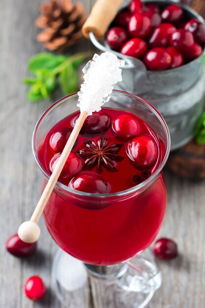 Fresh cranberry juice with cinnamon and anise in glass jars on the old wooden surface. Selective focus.Top view.