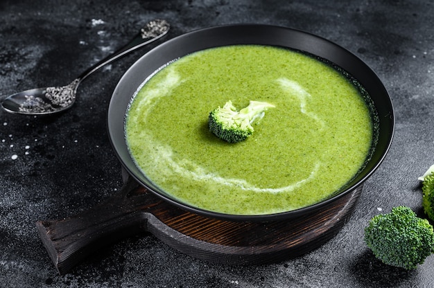 Fresh cream broccoli and pea soup in plate . Black background. Top view.