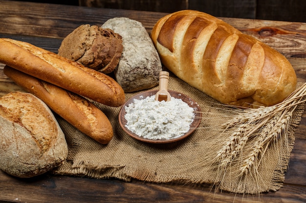 Fresh crispy bread with flour on a wooden table