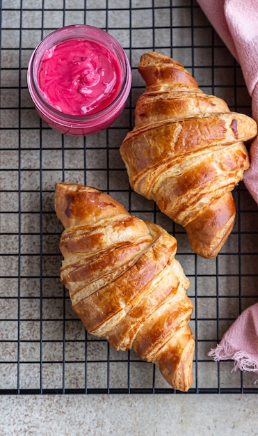 Fresh crispy croissants with pink honey on black metal grille. Top view.