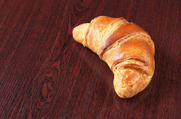 Fresh croissant on brown wooden desk with copy space