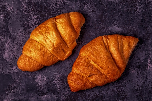 Fresh croissant on dark table.