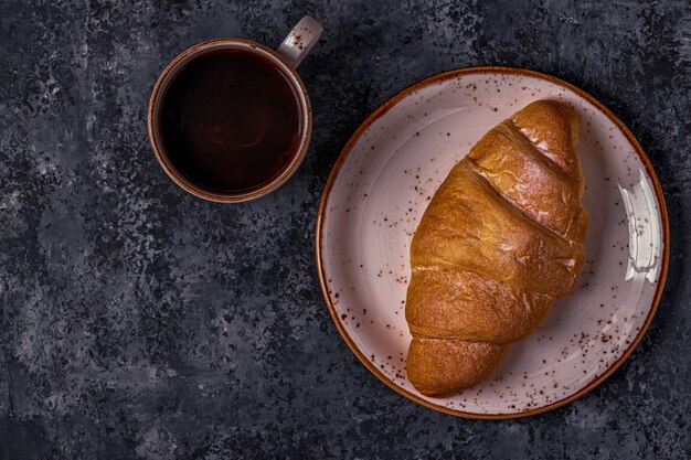 Fresh croissant on dark table.