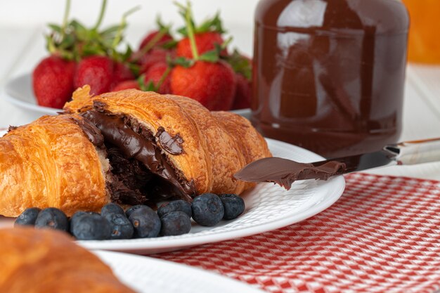 Fresh croissant decorated with berries on white wooden board