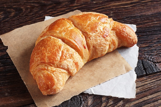 Fresh croissant on old wooden table closeup