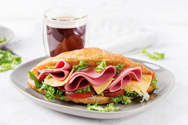 Fresh croissant or sandwich with salad ham and cheese on light background