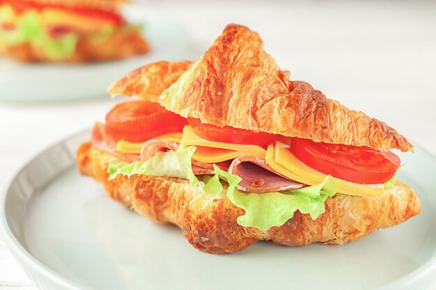 Photo fresh croissant with ham and lettuce on white wooden background