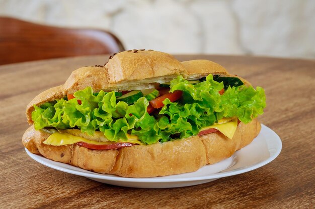 Photo fresh croissant with ham and lettuce on a wooden table in a cafe