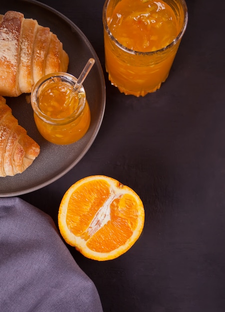 写真 焼きたてのクロワッサンパン、オレンジ、オレンジジャム。朝食のコンセプトです。上面図。コピースペース