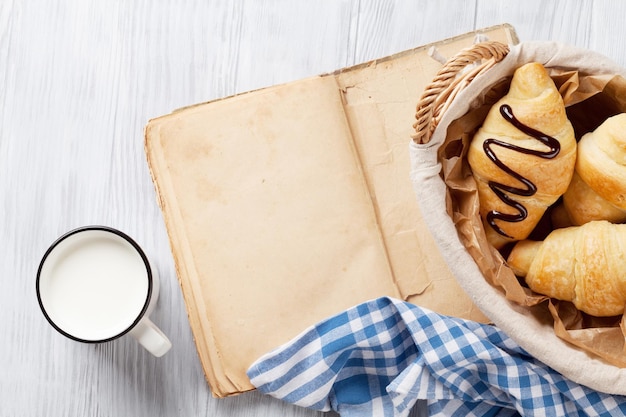 Fresh croissants milk and old book