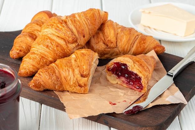 Fresh croissants with berry jam on dark wooden board