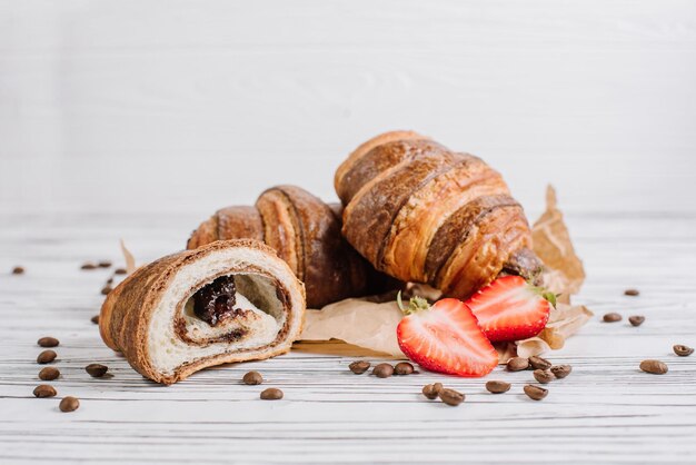 Fresh croissants with chocolate and strawberries on the wooden background