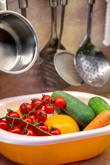 Fresh croped vegetables in colander on kitchen table