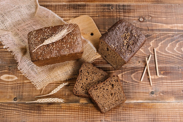 Fresh crunchy bread loafs and pieces on the wooden background