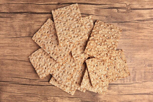 Fresh crunchy crispbreads on wooden table flat lay