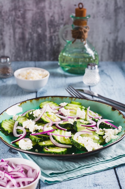 Photo fresh cucumber ricotta and red onion salad on a plate on the table vertical view