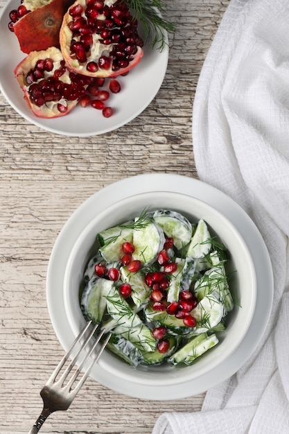 Photo fresh cucumber salad with dill and pomegranate kernels, in yoghurt sauce
