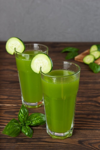 Fresh cucumber water with basil and lemon in glasses on wooden table