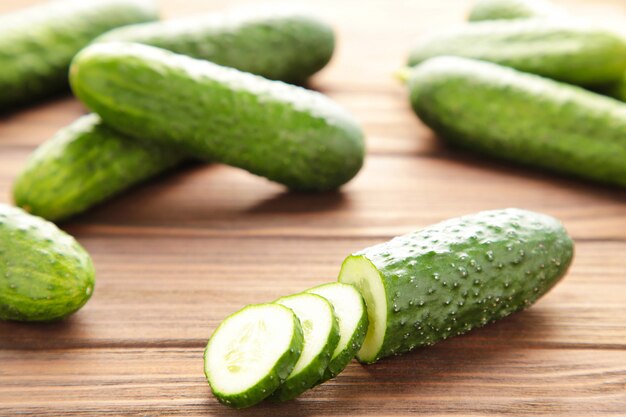Fresh cucumber with slices on brown wooden background.
