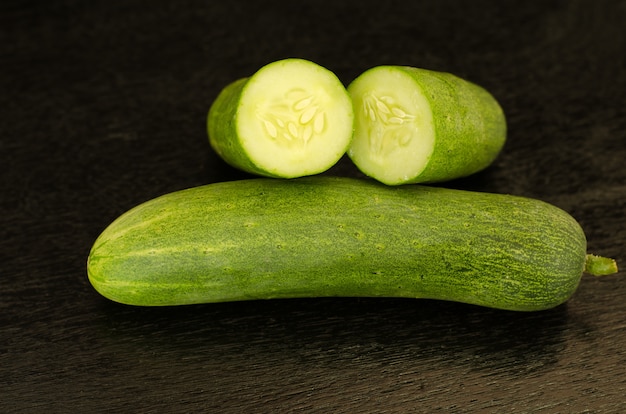 Fresh cucumbers on black wooden background 