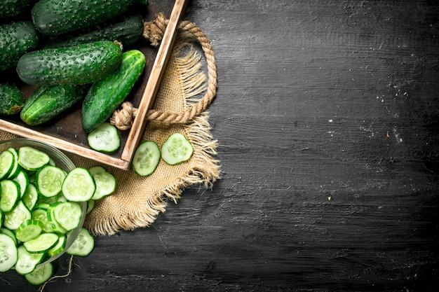 Fresh cucumbers in a wooden tray. On a black chalkboard.