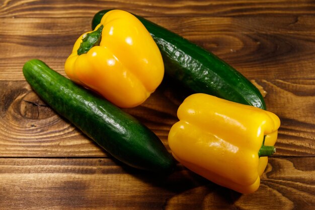 Fresh cucumbers and yellow peppers on wooden table