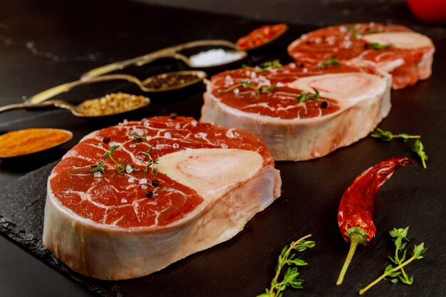 Fresh cut beef shank in bone and seasonings on black board.