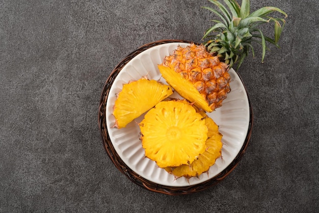 Foto ananas tagliato fresco con foglie tropicali su uno sfondo grigio