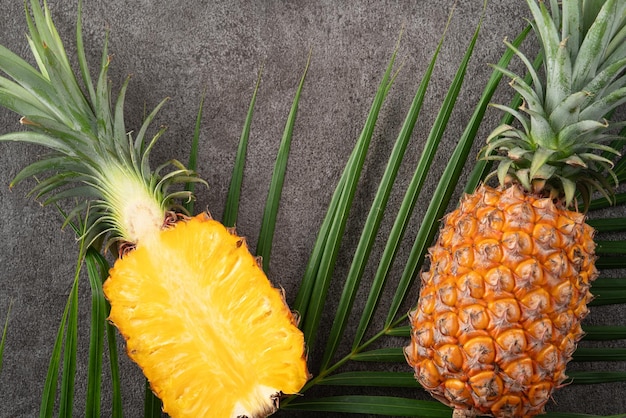 Foto ananas tagliato fresco con foglie tropicali su uno sfondo grigio