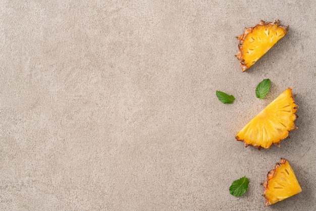 Foto ananas tagliato fresco con foglie tropicali su uno sfondo grigio