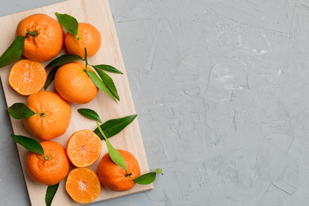 Fresh cutted clementines and whole mandarin over round plate on colored background Food and drink ingredients preparing healthy eating theme top view vith copy space