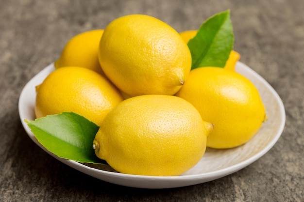 Fresh cutted lemon and whole lemons over round plate on colored background Food and drink ingredients preparing healthy eating theme top view vith copy space