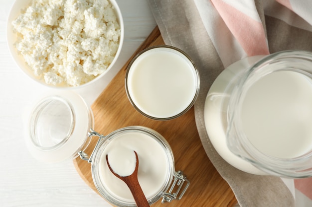 Fresh dairy products, board and towel on white wooden table