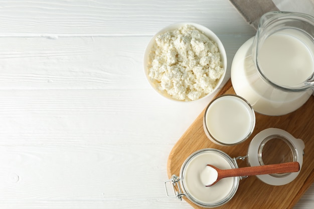 Fresh dairy products, board and towel on white wooden table