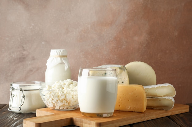 Fresh dairy products and cutting board on wooden background