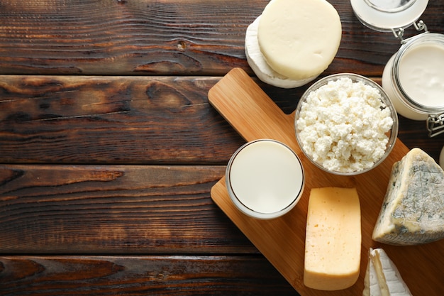 Fresh dairy products and cutting board on wooden background