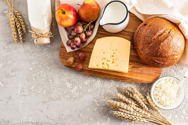 Fresh dairy products a loaf of bread a bouquet of ears of corn apples for the celebration of Jewish shavuot top view a copy space