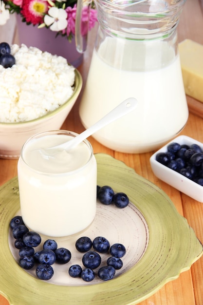 Fresh dairy products with blueberry on wooden table closeup