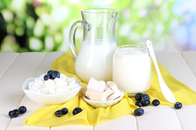 Fresh dairy products with blueberry on wooden table on natural background