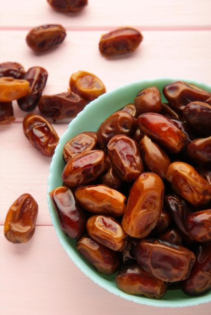 Photo fresh dates in mint bowl on pink background vertical photo