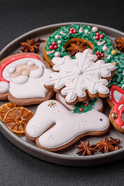 Fresh delicious baked christmas or new year gingerbread cookies with bright color themed pattern on dark concrete background