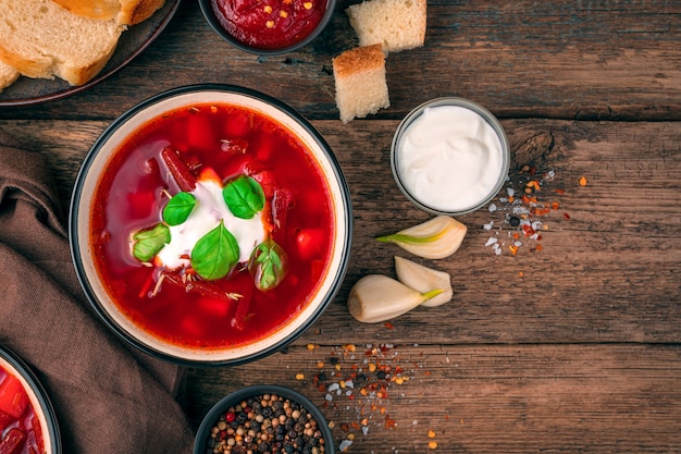 Fresh, delicious beetroot soup with cream and basil on a brown wooden background. Cooking concept.