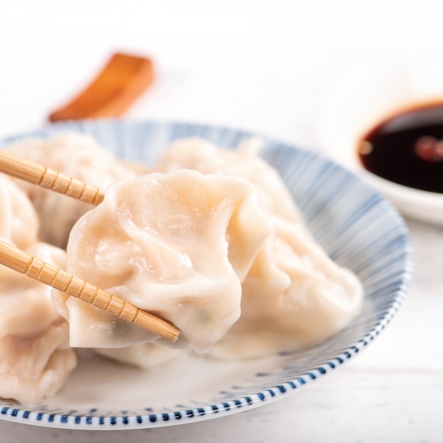 Fresh delicious boiled pork shrimp gyoza dumplings on white background with soy sauce and chopsticks close up lifestyle Homemade design concept