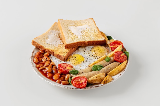 fresh delicious breakfast on a plate isolated on a white background. tasty fried eggs, viennese sausages, cherry tomatoes and spinach