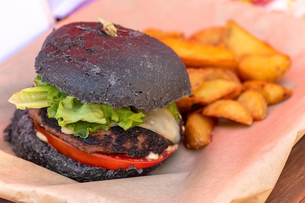 Fresh delicious grilled black burger on wooden table Street food festival